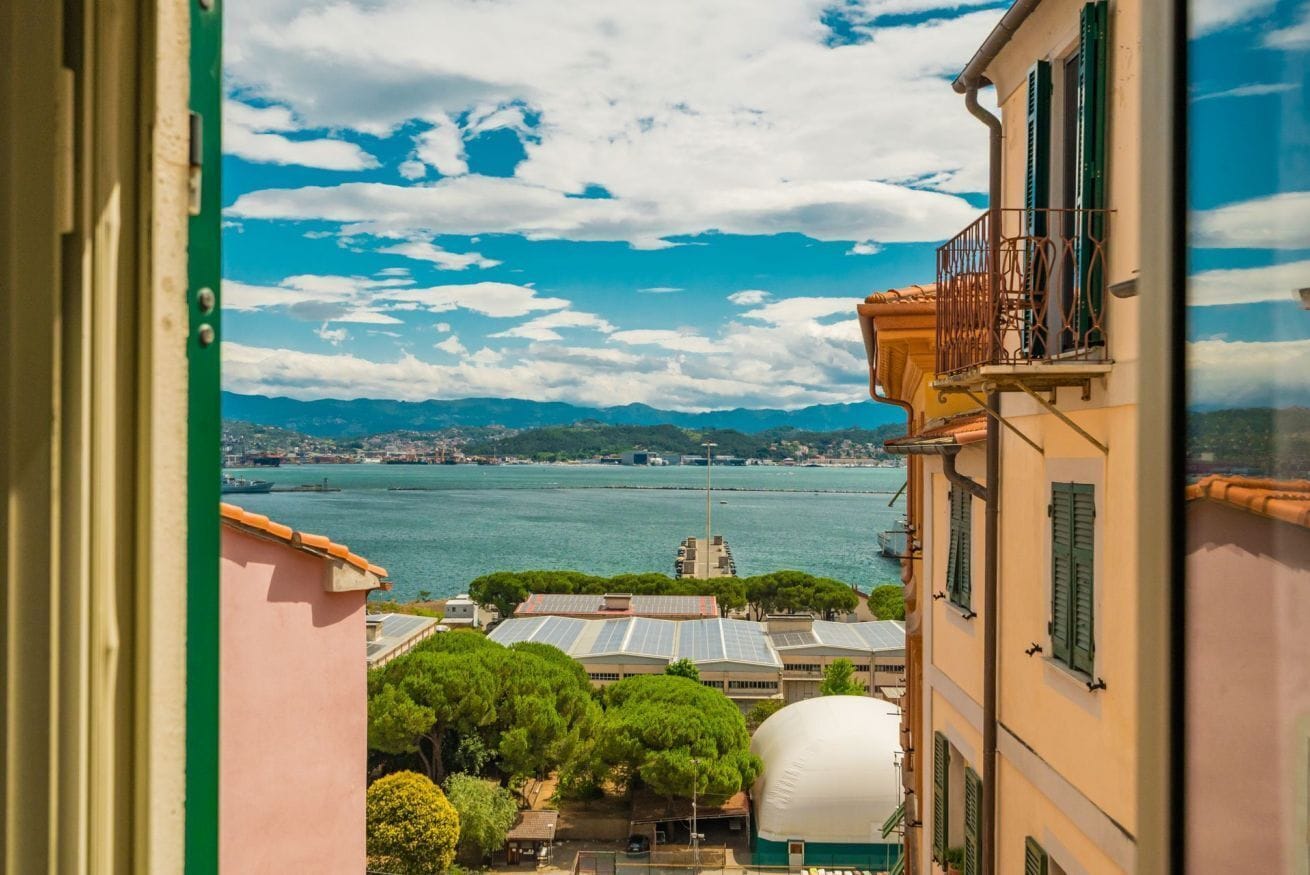 Une vue d’une ville côtière, avec ses bâtiments, une étendue d’eau et des montagnes à l’horizon.