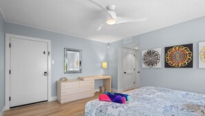 A bedroom with a bed, dresser, and artwork on the wall.