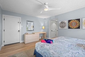 A bedroom with a bed, dresser, and artwork on the wall.