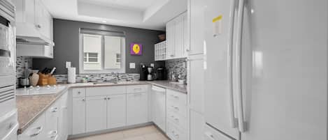 Una cocina moderna con armarios blancos, un refrigerador de acero inoxidable y un salpicadero de azulejos.