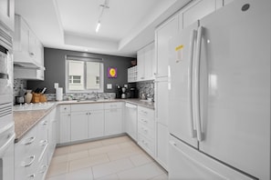 A modern kitchen with white cabinets, a stainless steel refrigerator, and a tiled backsplash. - Sea Club III #4 2B / 2B Direct Beachfront Condo by RVA (Longboat Key)