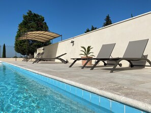 Ein Schwimmbecken mit Liegestühlen und einer Pergola.