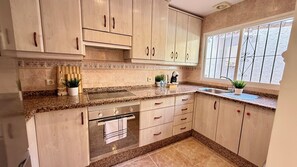A kitchen with light wood cabinets, a granite countertop, a built-in oven, and a window with a view. - White Boho Banus, by Sol Maestranza (Marbella)