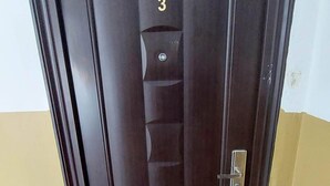 A dark wooden door with a number '3' above it, a metal handle, and a doormat with 'SWEET HOME' written on it.