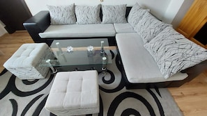 A modern living room with a sectional sofa, a glass coffee table, and matching ottomans.