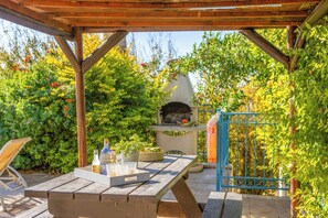 Eine Terrasse im Freien mit einem Holztisch, einem Grill und einem blauen Tor.