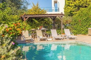 Ein Poolbereich mit Liegestühlen, einer Pergola und einem Schild, das darauf hinweist, dass das Springen verboten ist.