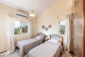 Habitación con dos camas, ventilador de techo, aire acondicionado y una ventana con cortinas.