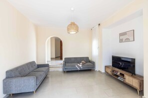 A living room with two grey sofas, a television on a wooden stand, and a woven light fixture. - Coralia Dream 1 - Three Bedroom Villa, Sleeps 6 (Peyia)