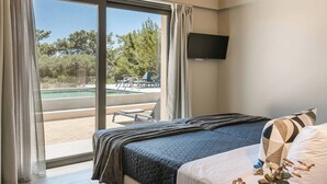 A hotel room with a bed, a TV mounted on the wall, and a view of an outdoor pool area. - Sea Melody - Two Bedroom Villa, Sleeps 4 (Ionian Islands)