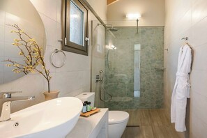 Ein modernes Badezimmer mit einer Duschkabine, einem weißen Waschbecken und einer Toilette.
