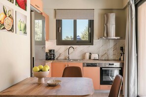 A modern kitchen with a dining area, featuring a marble backsplash, a built-in oven, and a window with a view. - Sea Harmony - One Bedroom Villa, Sleeps 2 (Ionian Islands)