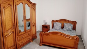 Une chambre à coucher avec un lit en bois, une armoire avec un miroir et une table de chevet.