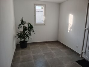 A room with a potted plant, a window, and a door.