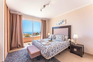 A hotel room with a bed, a bench, a nightstand, and a view of the sea. - Villa Roxiane - Three Bedroom Villa, Sleeps 6 (Adeje)