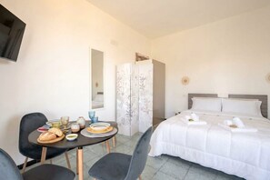 Ein Hotelzimmer mit Bett, Esstisch mit Stühlen, Fernseher und Kleiderschrank.