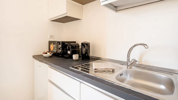Una cocina moderna con un lavamanos de acero inoxidable, una cafetera y un hervidor.