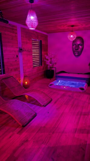 Ein Zimmer mit Holzboden, einer Whirlpool-Badewanne, einem Massagesessel und einer an der Wand befestigten Skulptur.