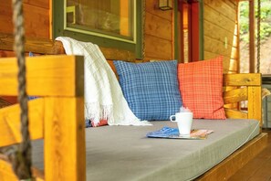 A wooden cabin interior with a bed, pillows, a cup, and a magazine. - 🎱 Riversong Elegance | Game Room, Hot Tub & Sleeps 12, Minutes to Dollywood 🏔️ (Sevierville)
