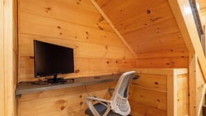 A wooden cabin interior with a desk, chair, and a television. - 🎱 Riversong Elegance | Game Room, Hot Tub & Sleeps 12, Minutes to Dollywood 🏔️ (Sevierville)