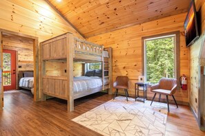Une cabine équipée d’un lit superposé, d’une petite table avec des chaises et d’un extincteur.