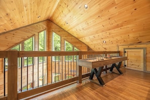 A wooden interior with a ping pong table, large windows, and a balcony. - 🎱 Riversong Elegance | Game Room, Hot Tub & Sleeps 12, Minutes to Dollywood 🏔️ (Sevierville)