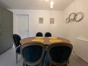 Ein Esszimmer mit einem runden Holztisch, sechs Stühlen und gelben Platzsets.