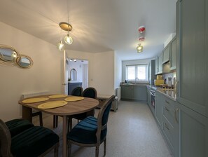 A compact kitchen with grey cabinets, a dining area with a round table and chairs, and pendant lighting. - 3-Bed Home | Sleeps 5 | Free Parking | Newcastle - Pass the Keys (Newcastle)
