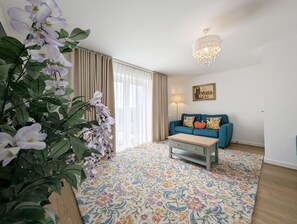En stue med sofa, sofabord, lysekrone og en stor blomster-gulvtæppe.