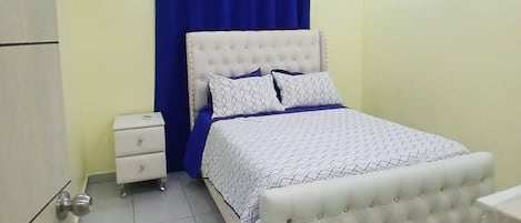 A bedroom with a bed, nightstand, and curtains.