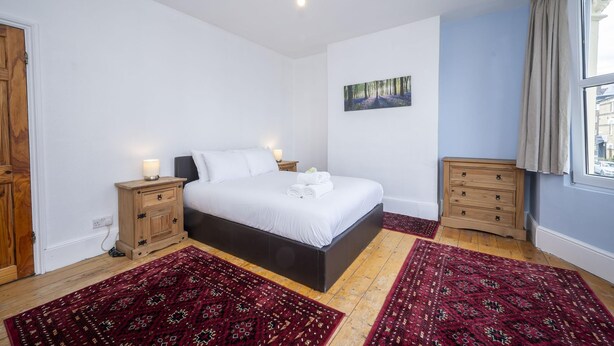 A bedroom with a bed, bedside tables, a nightstand, a window, and a painting on the wall. - Camberwell house - with Central London bus links - Pass the Keys (London)