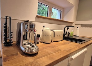 A kitchen with a coffee maker, two white electric toasters, a wine rack, and a window above the counter.