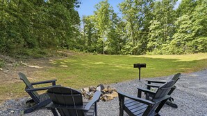 Two Adirondack chairs facing a fire pit with a signpost in a gravel area surrounded by trees. - Lovely 1-bedroom cabin with a hot tub in the mountains of Elizabethton (Elizabethton)