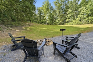 Two Adirondack chairs facing a fire pit with a signpost in a gravel area surrounded by trees. - Lovely 1-bedroom cabin with a hot tub in the mountains of Elizabethton (Elizabethton)