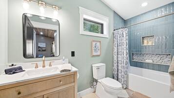 Une salle de bain équipée d’un meuble-lavabo, de toilettes, d’une baignoire et d’un rideau de douche.