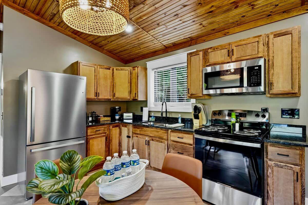 A kitchen with wooden cabinets, stainless steel appliances, and a dining area with a table and chairs.