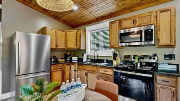 A kitchen with wooden cabinets, stainless steel appliances, and a dining area with a table and chairs.