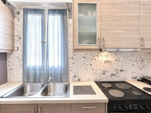 A modern kitchen with a double sink, a stove, and wooden cabinets. - Transit Hub Pad - Steps to Metro -Sleeps 3 by ΜΡS (Athina)