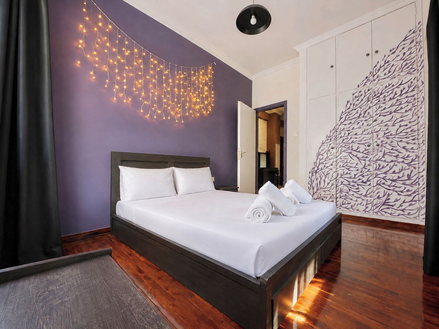 Habitación de hotel con cama, lámpara de pared, armario y pared con diseño.