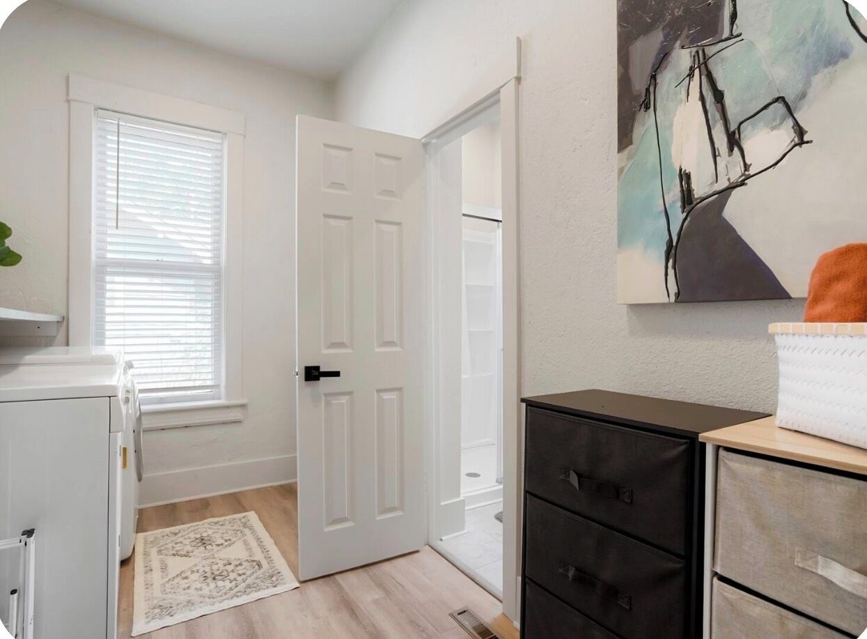 Um quarto com uma porta branca, um radiador branco, um armário preto e um quadro na parede.