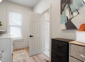 A room with a white door, a white radiator, a black cabinet, and a painting on the wall.
