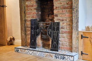 A fireplace with a brick wall, a tiled base, and a wooden door. - Host & Stay | Cuit's View (Great Ayton)