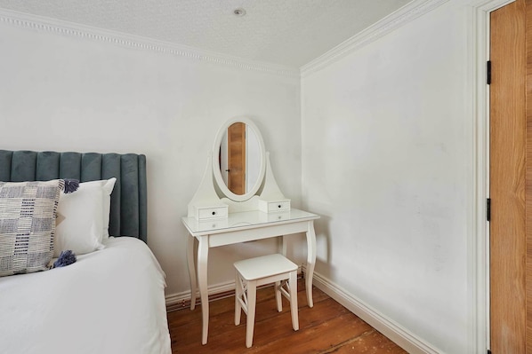 A bedroom with a bed, a white vanity with a mirror, and a small stool. - Host & Stay | Cuit's View (Great Ayton)