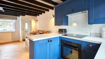 A modern kitchen with blue cabinets, a built-in oven, and a coffee machine.