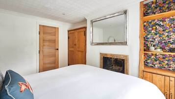 A bedroom with a wooden wardrobe, a mirror, a floral-patterned shelf, and a bed with a blue pillow.