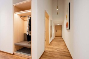 A hallway with a wooden floor, a built-in closet with a bench, and a door at the end. - Madrisella 13 Apartment (Gaschurn)