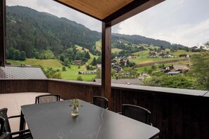 A terrace with a table and chairs, overlooking a village and mountains. - Madrisella 13 Apartment (Gaschurn)