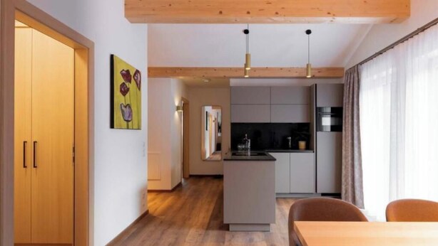 A modern kitchen with a central island, wooden flooring, and pendant lighting. - Apartment Piz Buin 31 (Gaschurn)