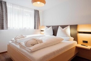A hotel room with a bed, bedside lamps, and a window with curtains. - Apartment Piz Buin 31 (Gaschurn)