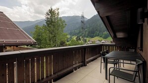 A balcony with a view of mountains, a table, and chairs. - Apartment Piz Buin 31 (Gaschurn)